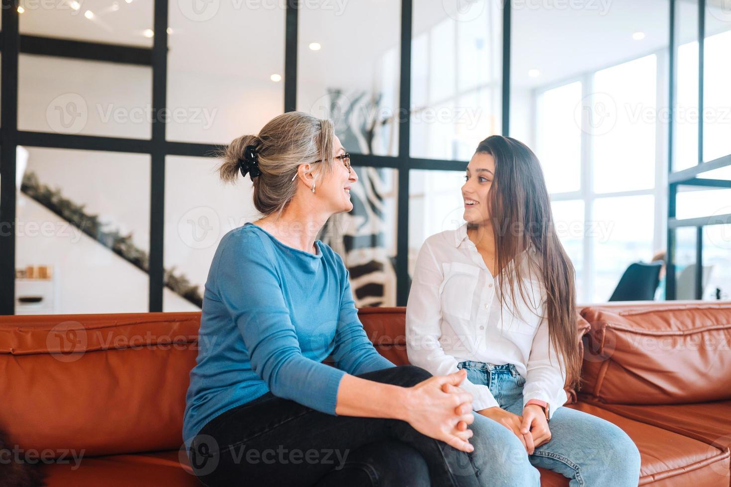 Young woman visiting grandmother at home, women talk photo