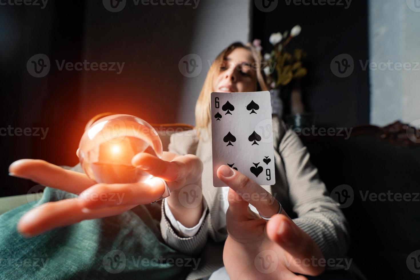 Woman in business suit holding crystal ball and six spade photo