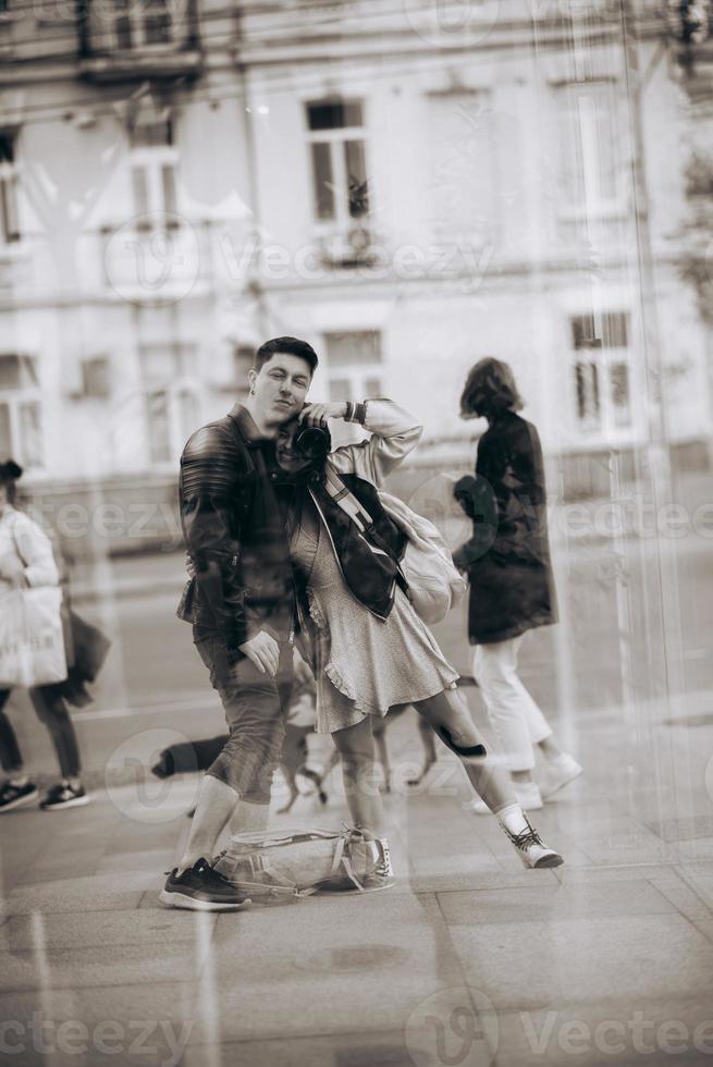 Young couple taking selfie in reflection of glass building photo