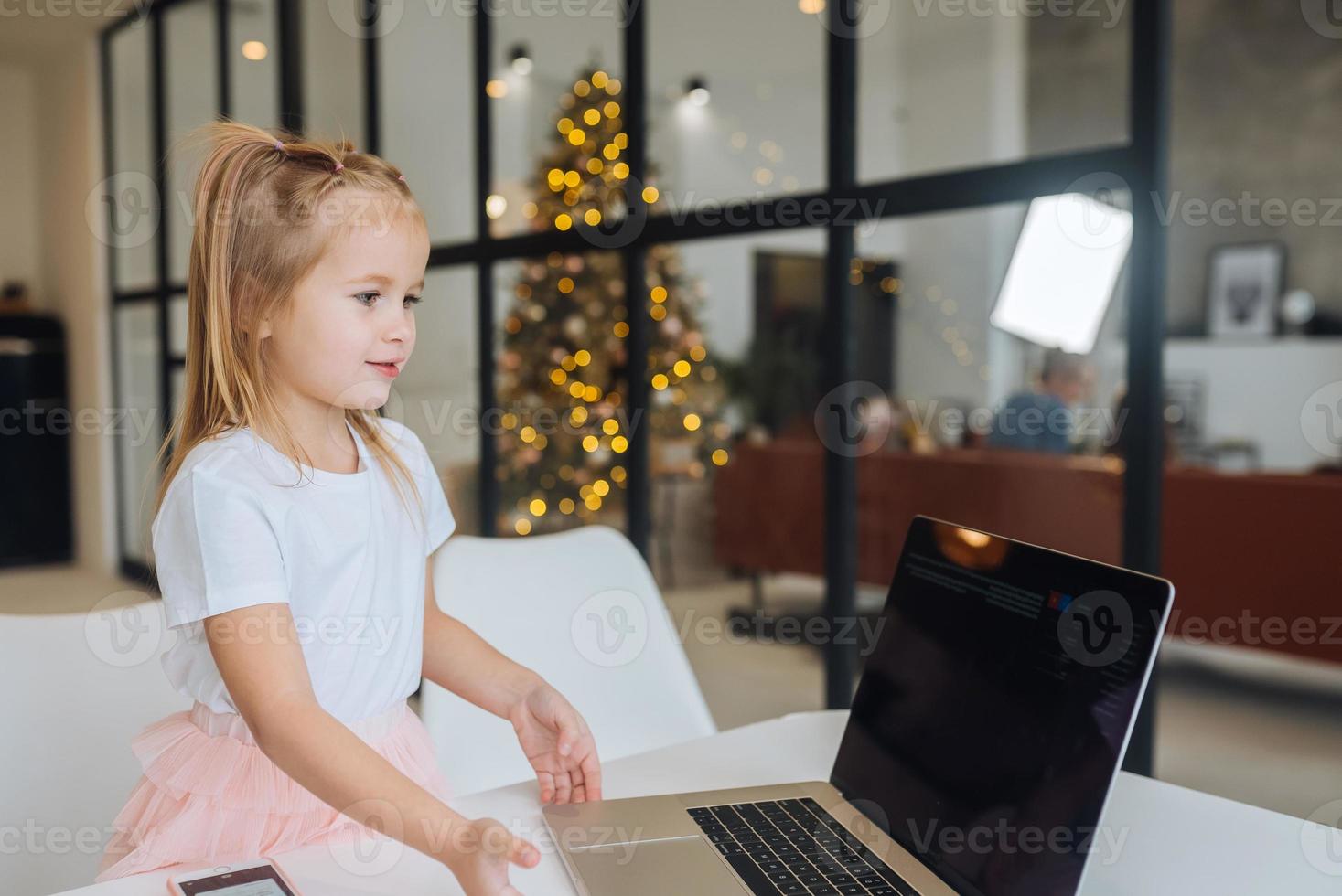 Little girl using tablet computer sitting at table photo