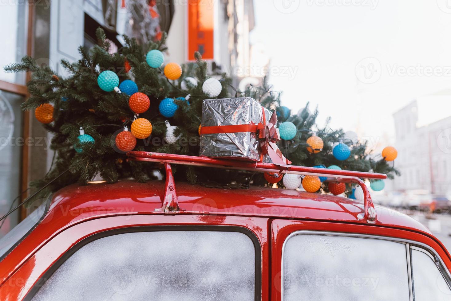 Red retro car with a Christmas tree fir tied to the roof. photo