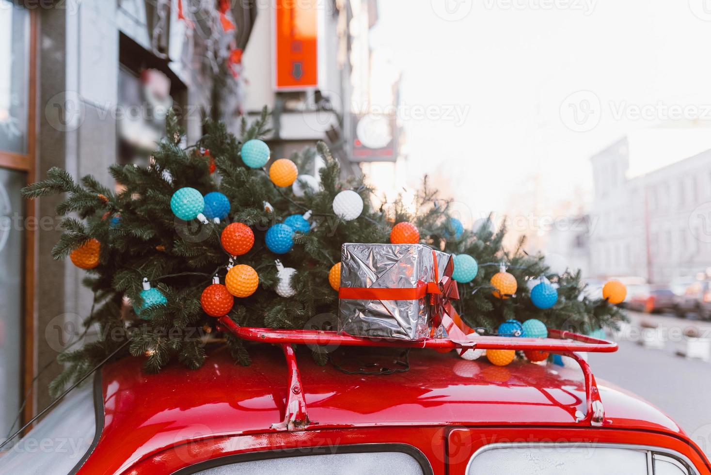 Red retro car with a Christmas tree fir tied to the roof. photo
