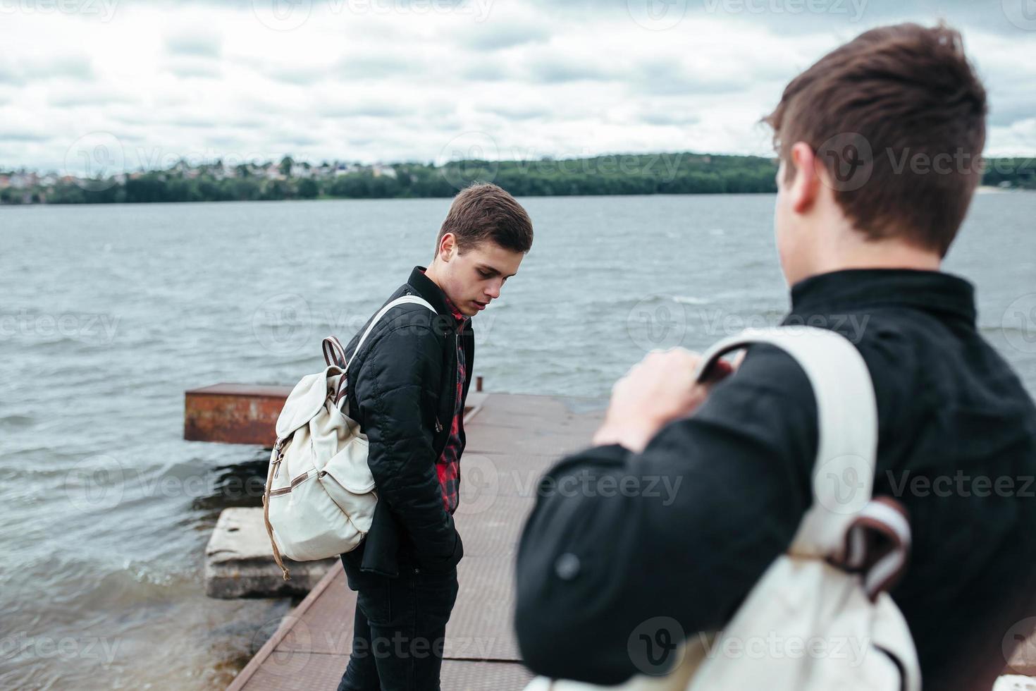 two young guys standing on a pier photo