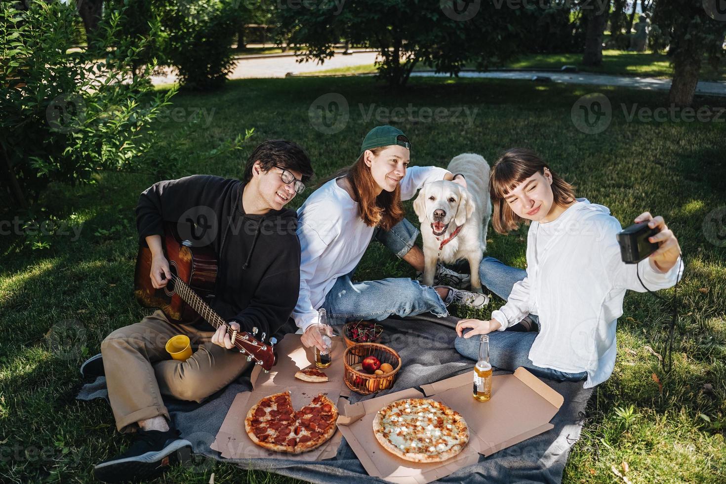 Company of beautiful young people and dog having an outdoor lunch. photo