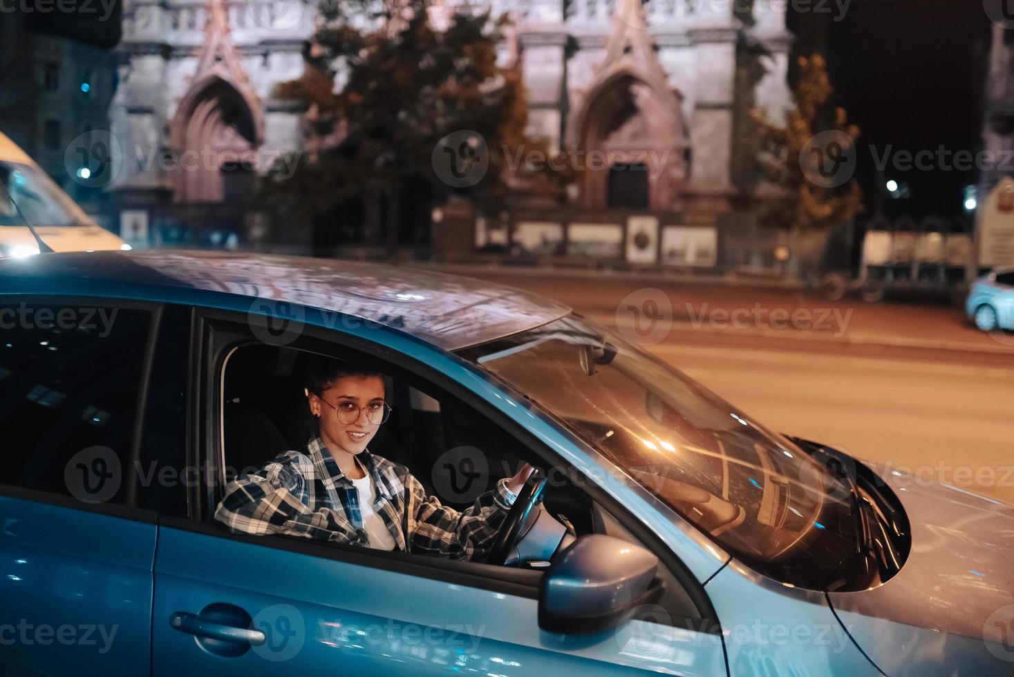 mujer conduciendo un coche por la noche en la ciudad foto