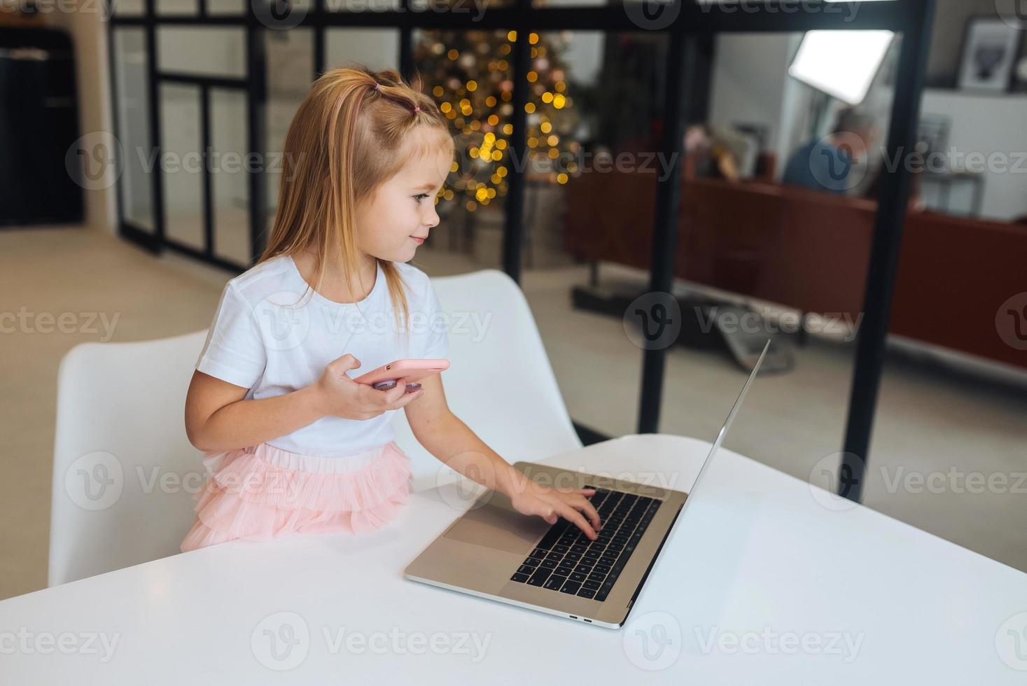 Little girl using tablet computer sitting at table photo