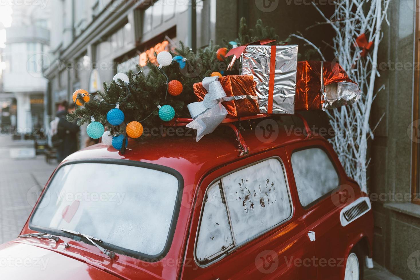 Red retro car with a Christmas tree fir tied to the roof. photo