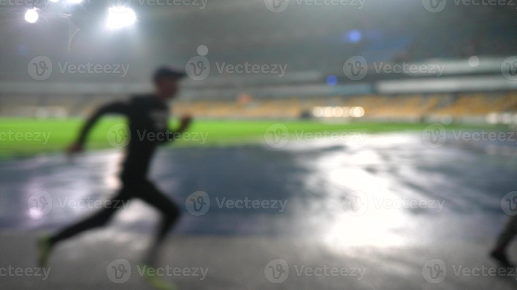 People go in for sports at night stadium in rainy weather photo
