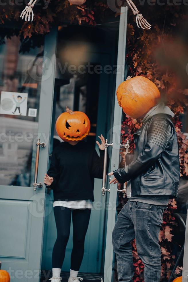 Couple with pumpkin heads posing on camu at the building photo