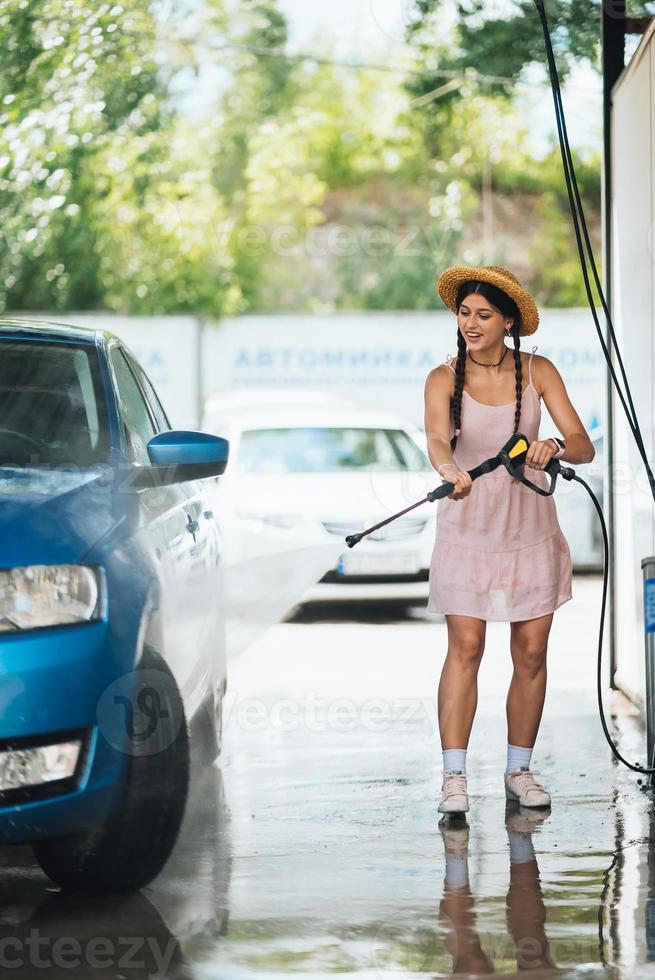 Brunette from a high-pressure hose washes the car photo