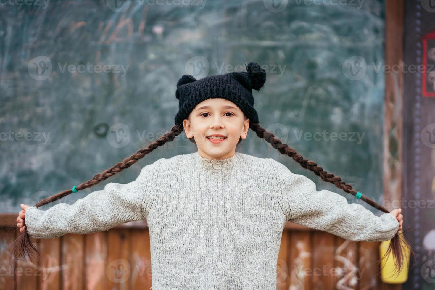 niña en un sombrero posando en el fondo de la pizarra de la escuela foto