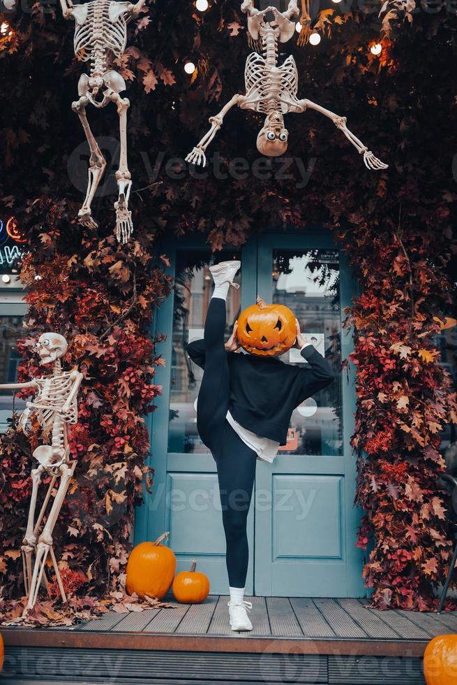 Girl with a pumpkin head posing at the door on the street photo
