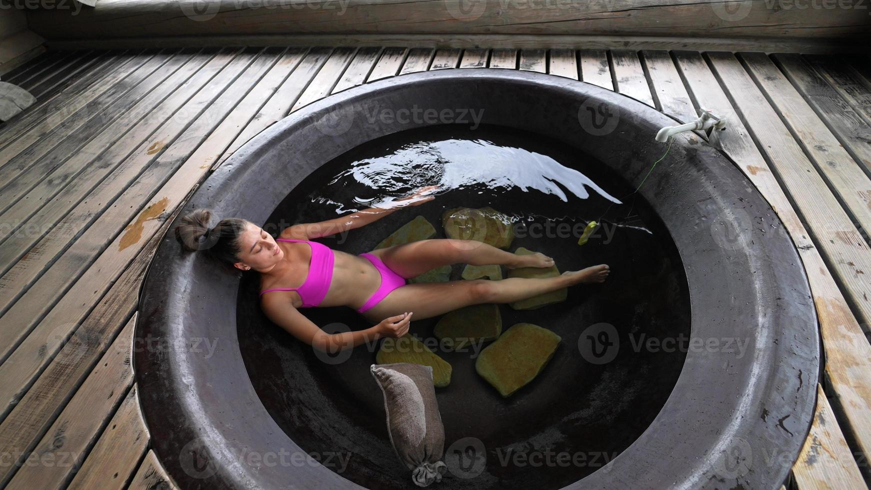 mujer relajándose en un baño redondo al aire libre. cuidado orgánico de la piel en baño caliente foto
