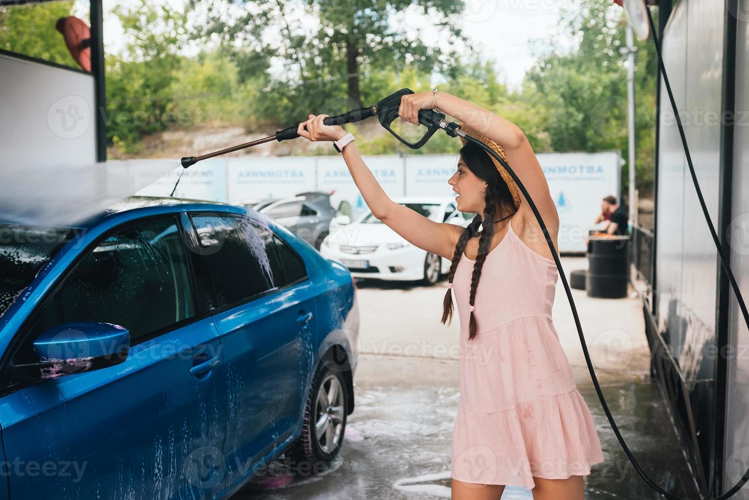 Brunette from a high-pressure hose washes the car photo