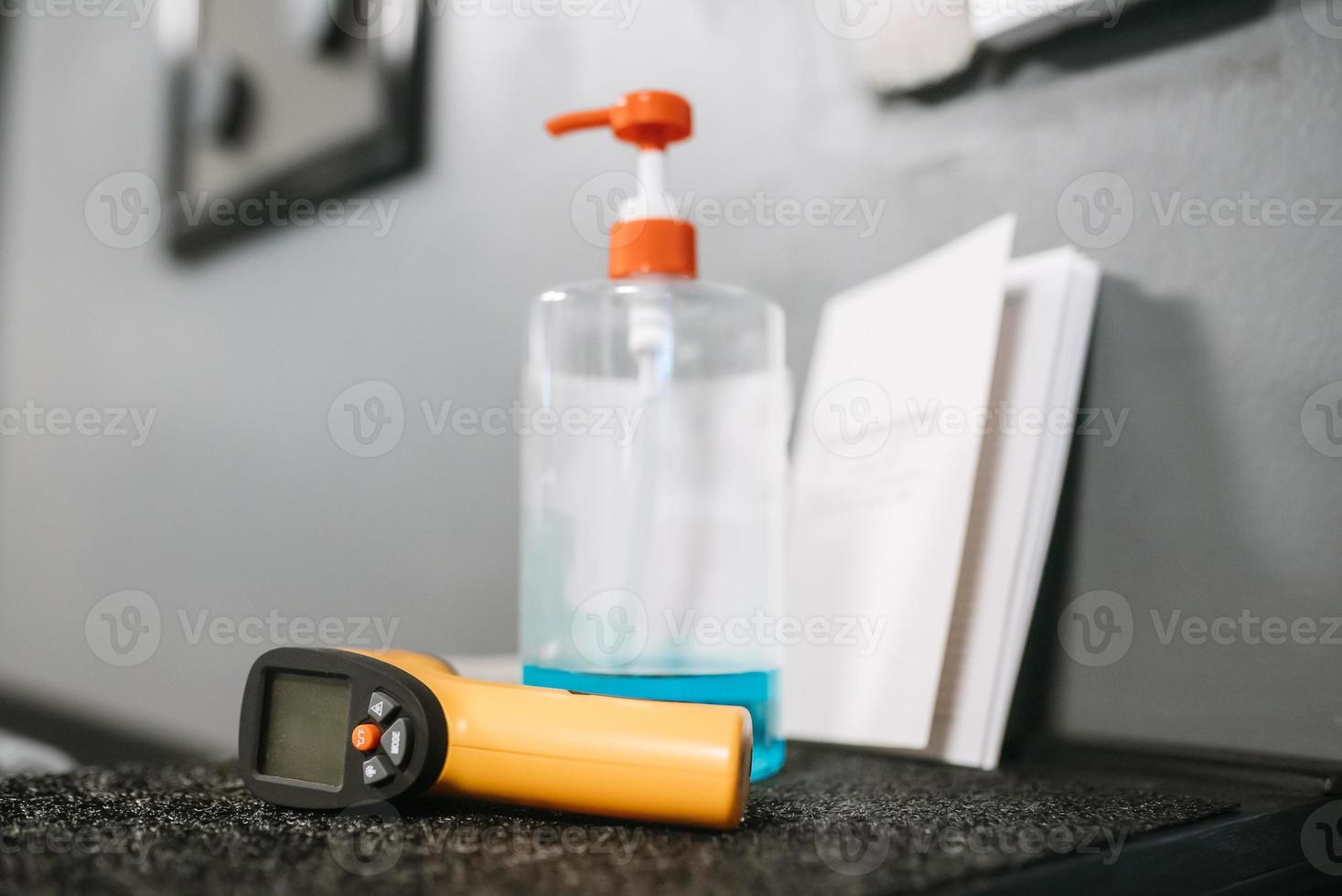 Electronic thermometer and sanitizer gel to wash hands on the table photo