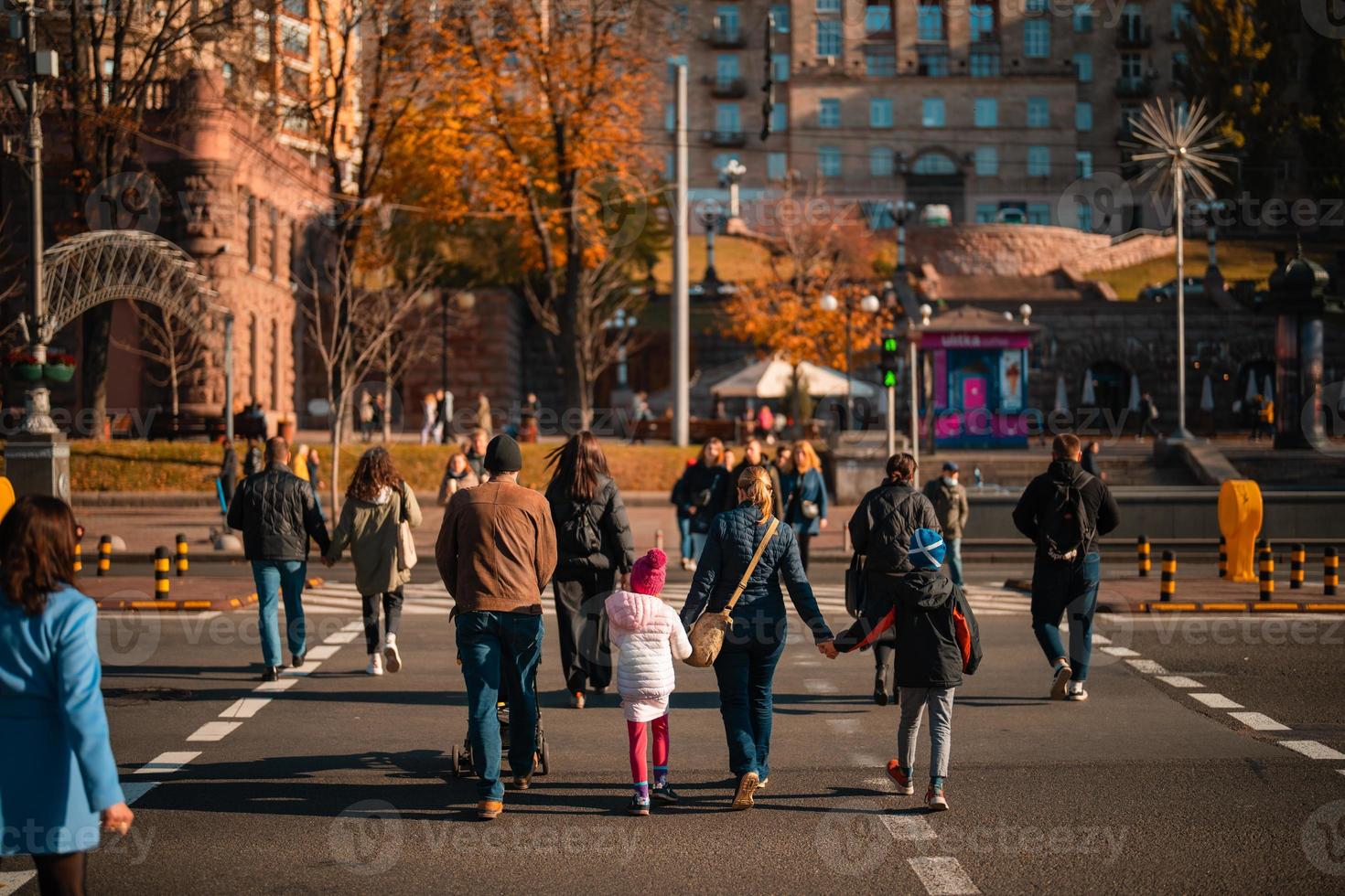 Lots of people crossing the street at the traffic lights. photo