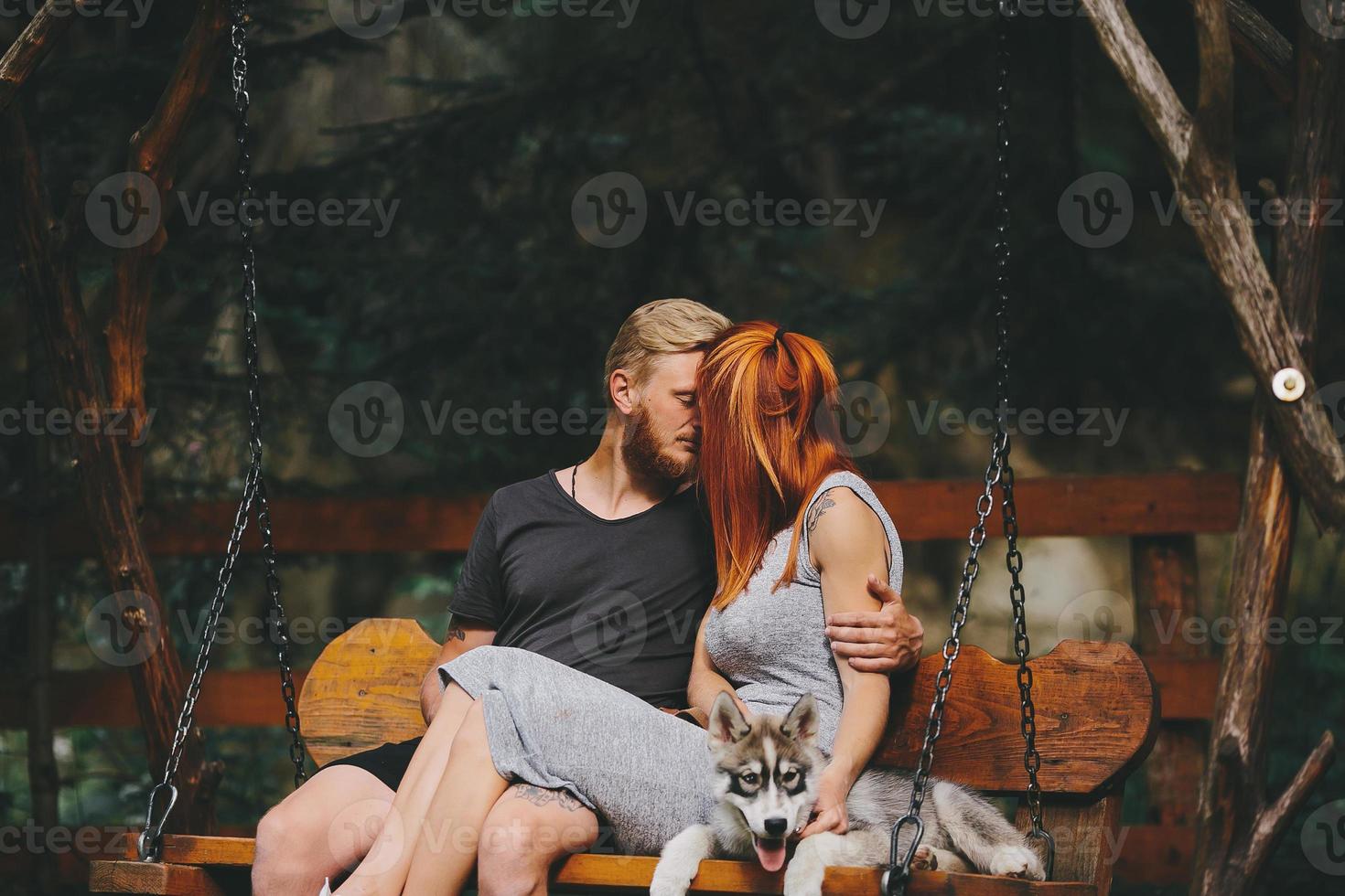 beautiful couple together with dog on a swing photo