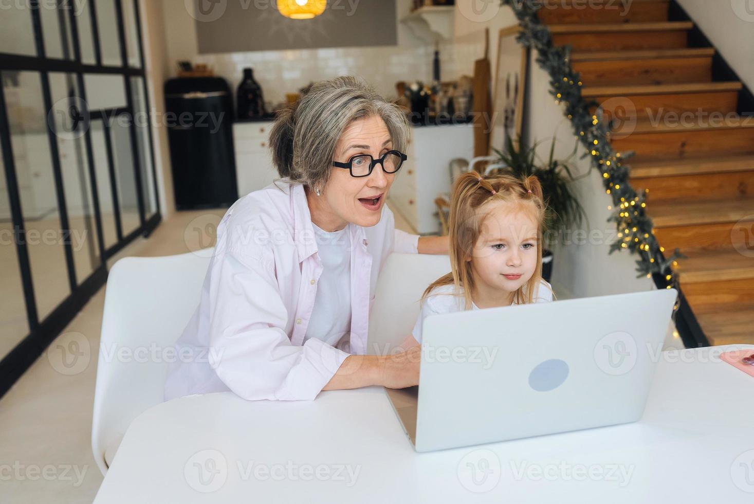 niño y abuela mirando la cámara con laptop foto