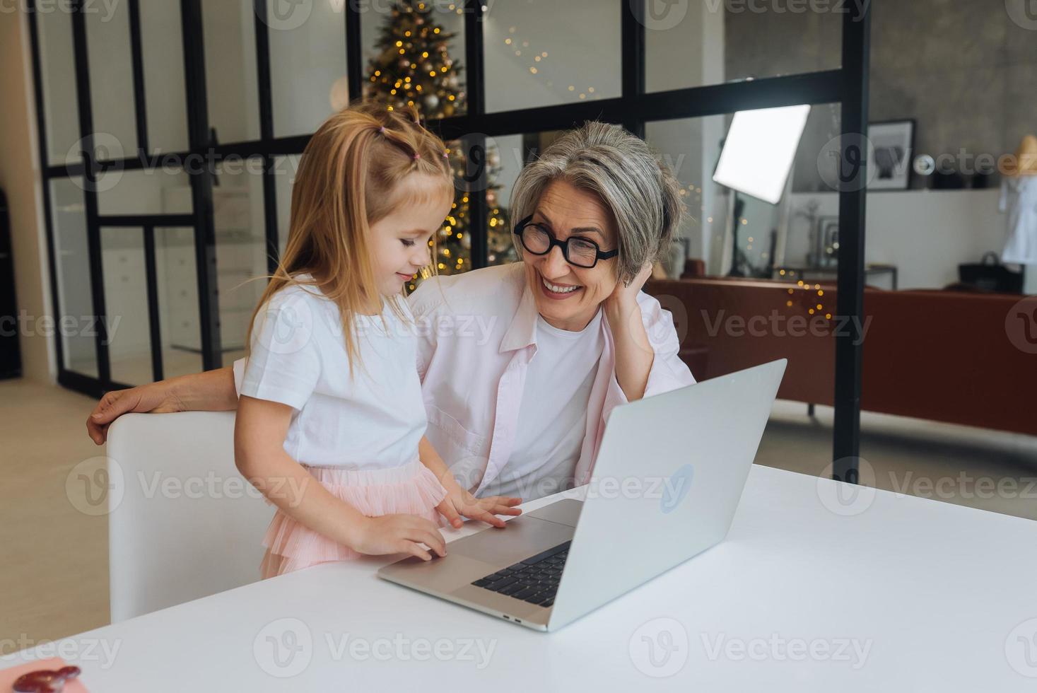 Child and granny looking at the camera with laptop photo