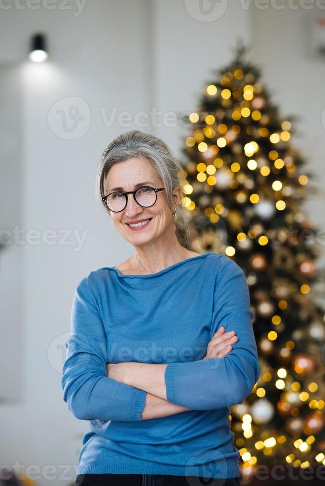 Elderly lady smiling and looking in camera, Xmas tree on background photo