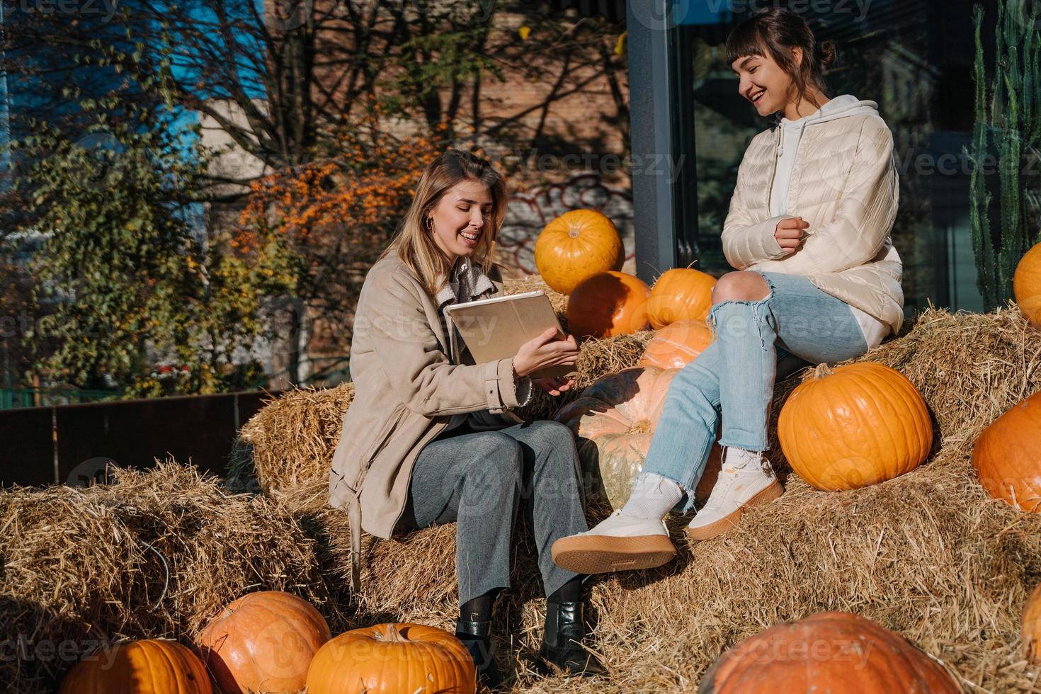 Girls have fun among pumpkins and haystacks on a city street photo