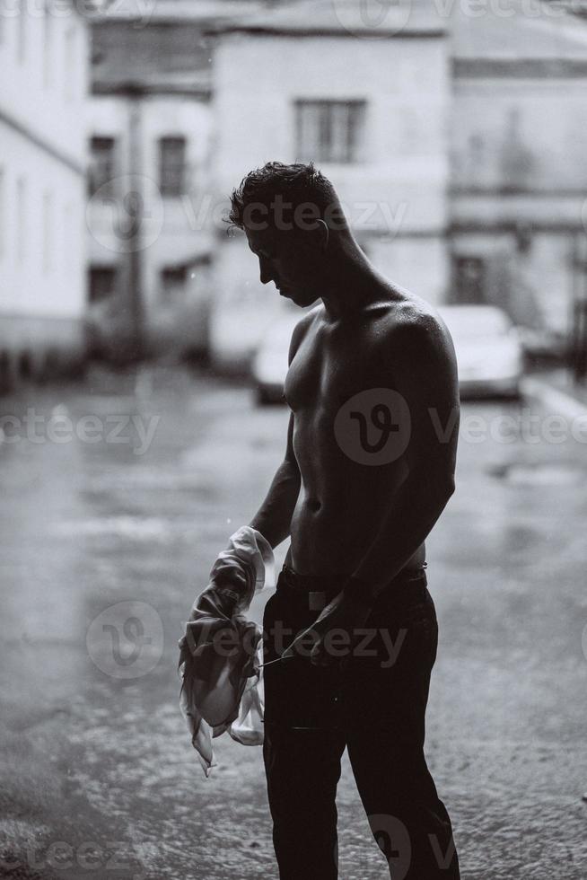 Portrait of carefree handsome young man is feeling free under the rain photo