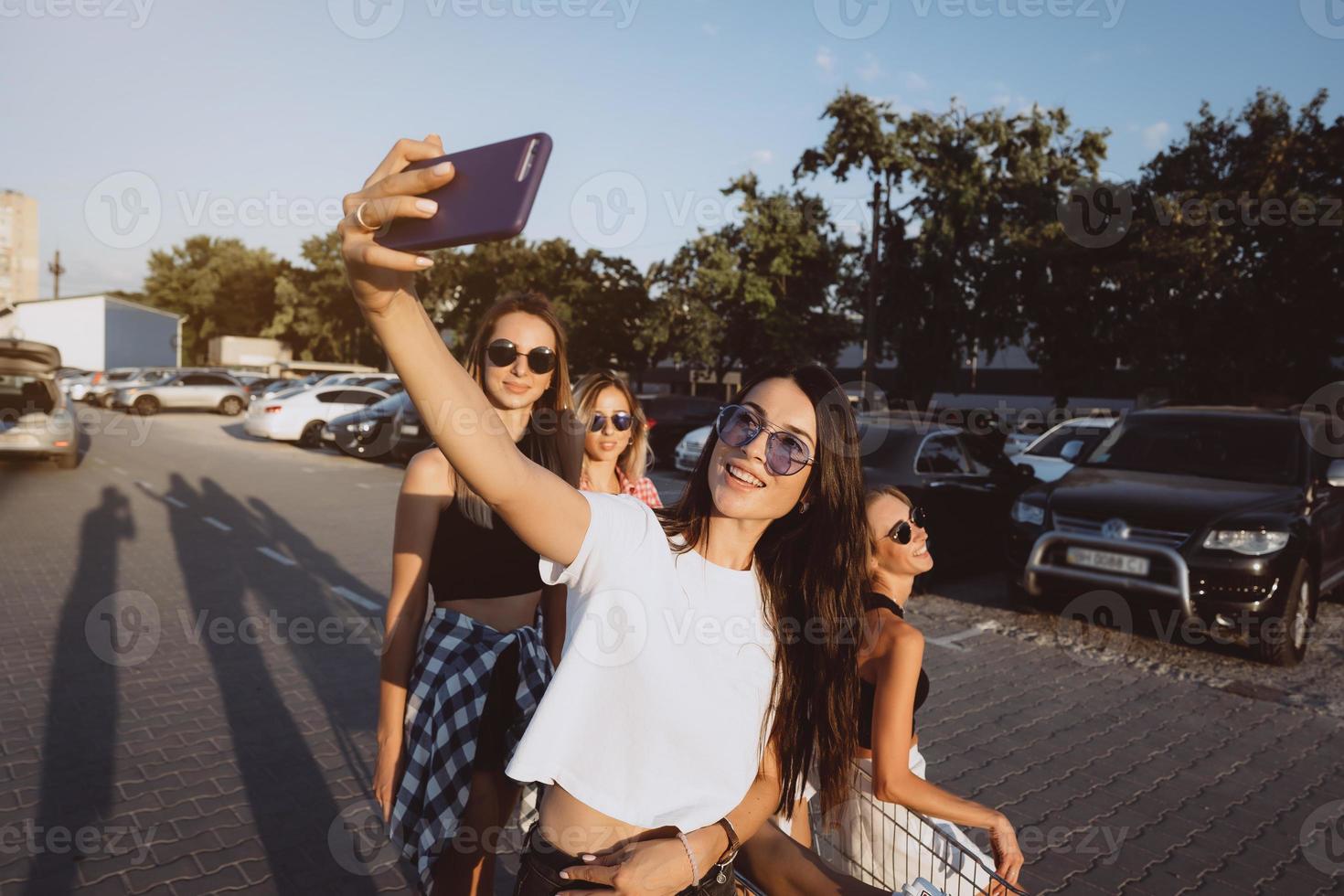 Five young girls have fun with a supermarket cart on a car park photo