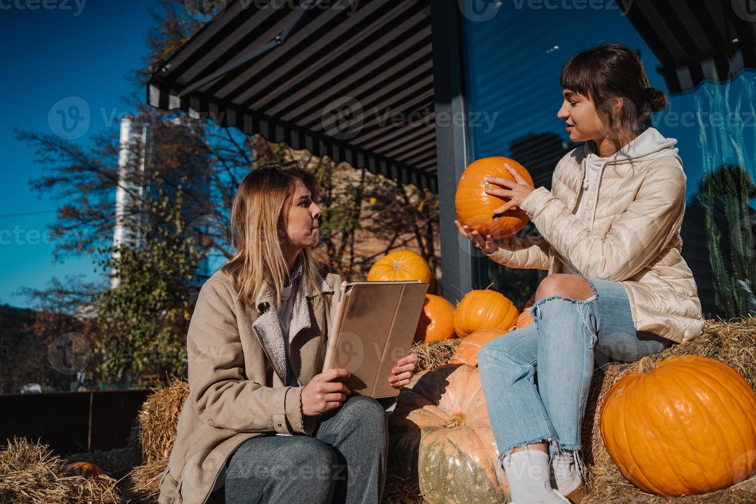 Girls have fun among pumpkins and haystacks on a city street photo