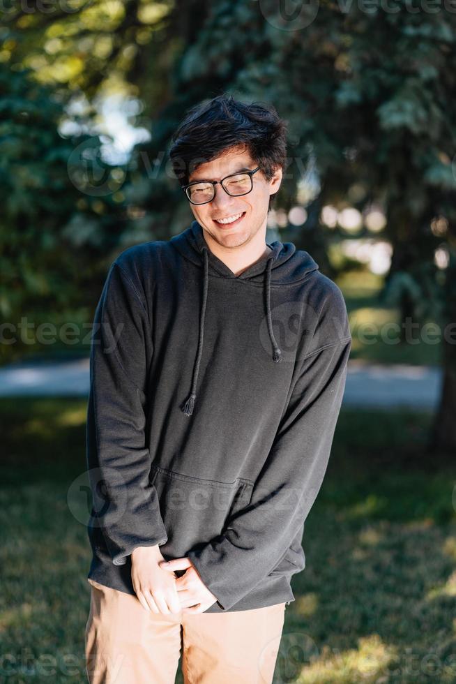 Portrait of happy young male student with glasses in casual outfit photo