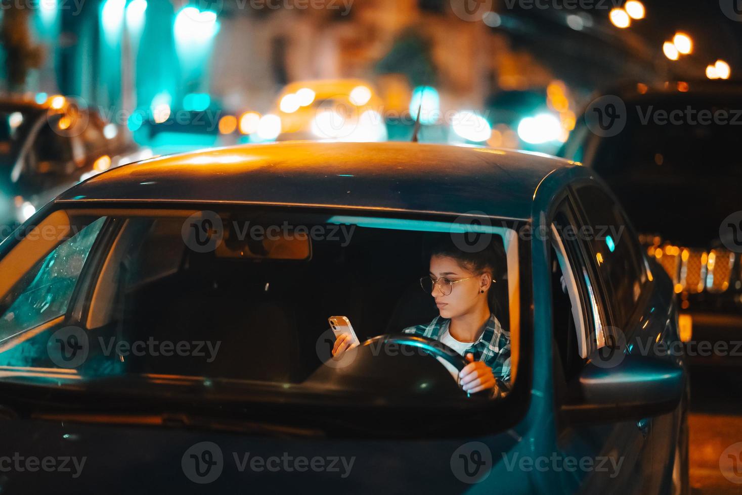 mujer conductora perdida que usa el teléfono móvil mientras conduce de noche. foto