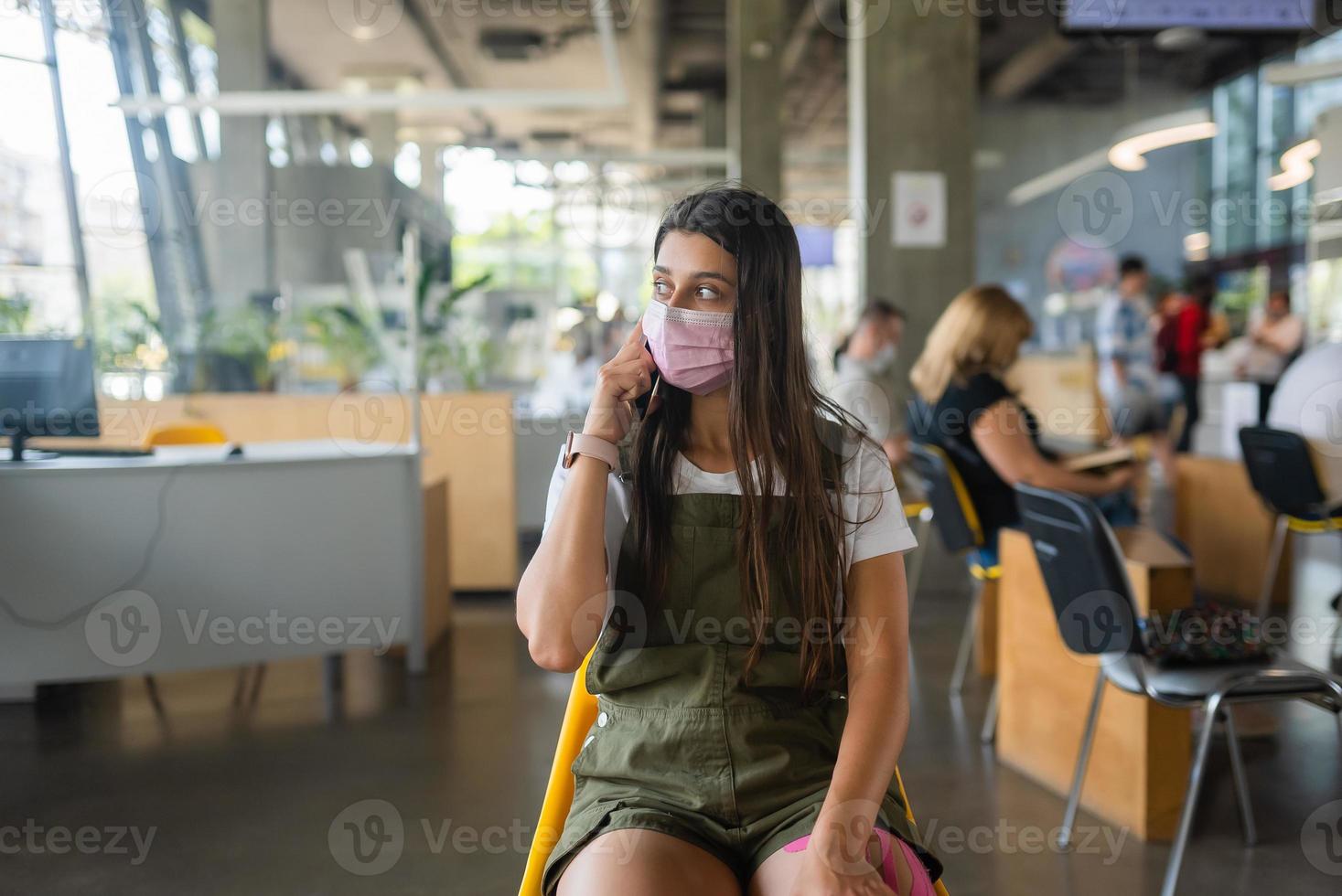 Young woman in face mask talking on mobile phone at indoor. photo