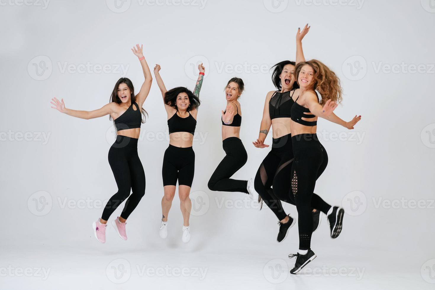 diverse models jump up, enjoying time together, look at camera photo