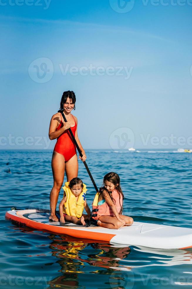madre con dos hijas de pie en una tabla de remo foto
