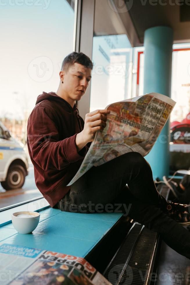 Portrait of man sitting at a cafe, reading newspapers and drinking coffee photo