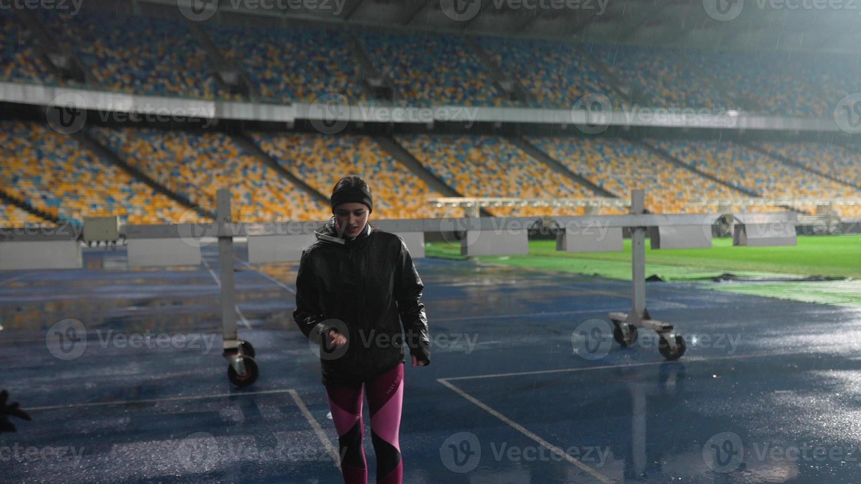 People go in for sports at night stadium in rainy weather photo