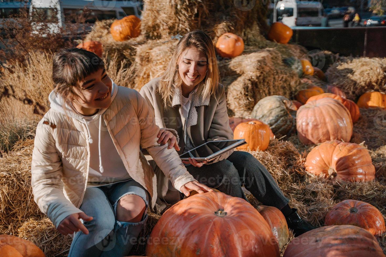 Girls have fun among pumpkins and haystacks on a city street photo