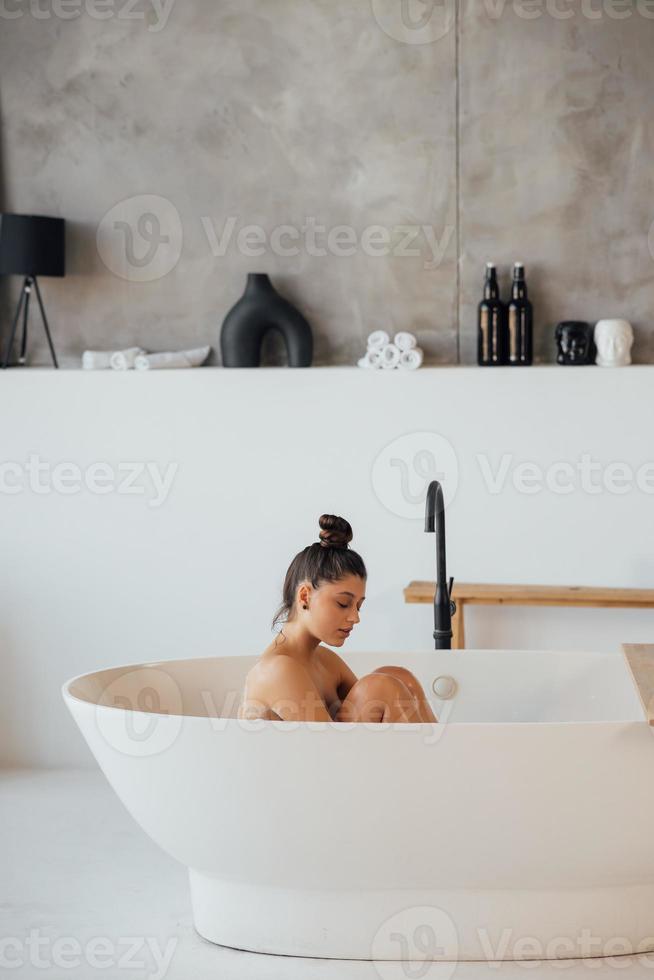 vista lateral de una mujer tomando un baño de espuma en casa foto