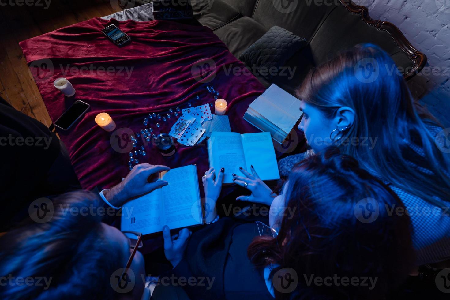Two women and a guy are reading a mysterious books, close view photo