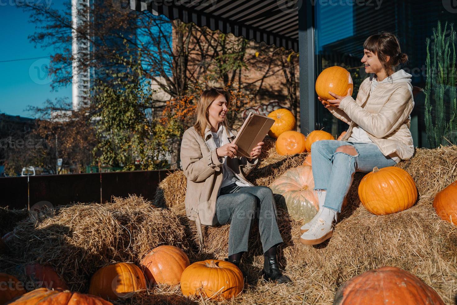 Girls have fun among pumpkins and haystacks on a city street photo