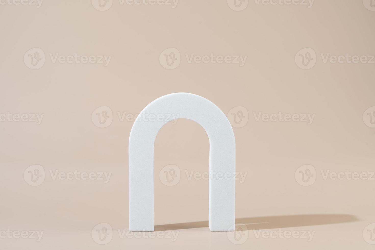 A white geometric shape in the form of the arch standing on a beige background photo