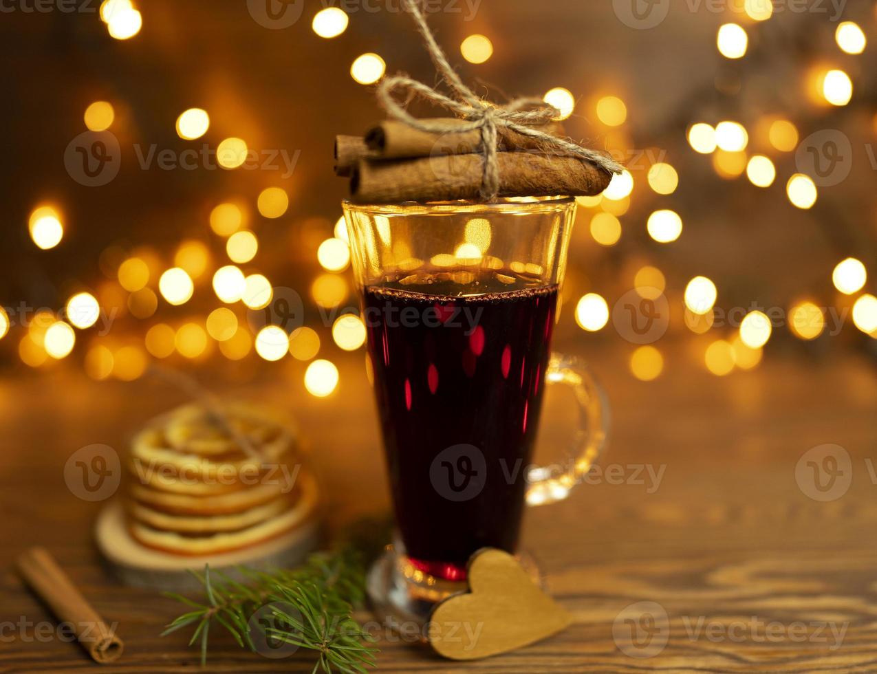 Mulled wine stands on a wooden table with bokeh lights on the background photo