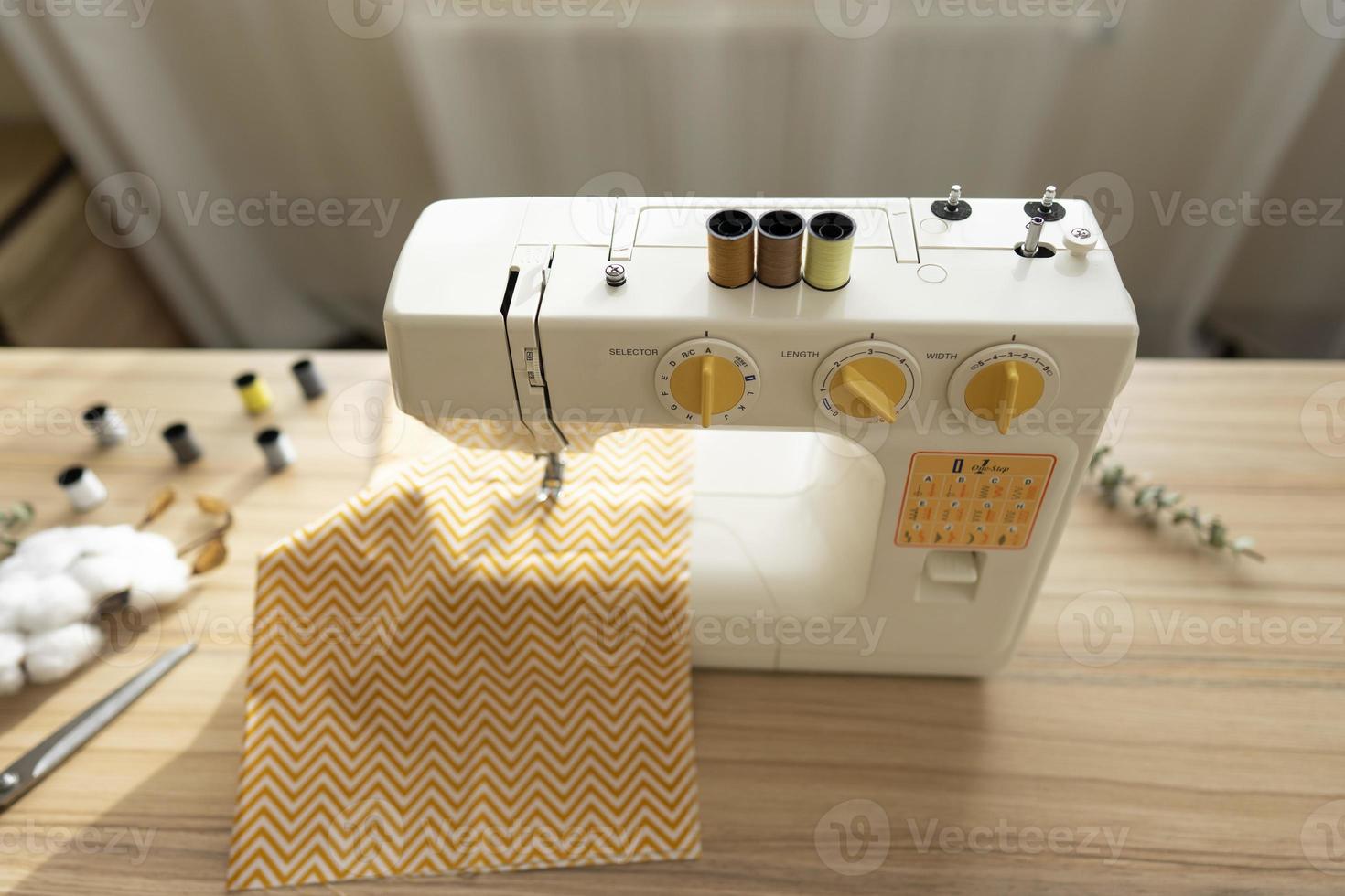 A white sewing machine stands on the table photo