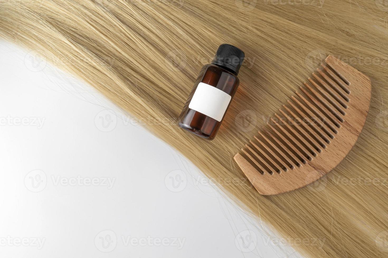 A hair care oil or serum in golden capsules lying on a strand of blond hair, product marketing mockup. A concept of hair care in a salon or at home photo