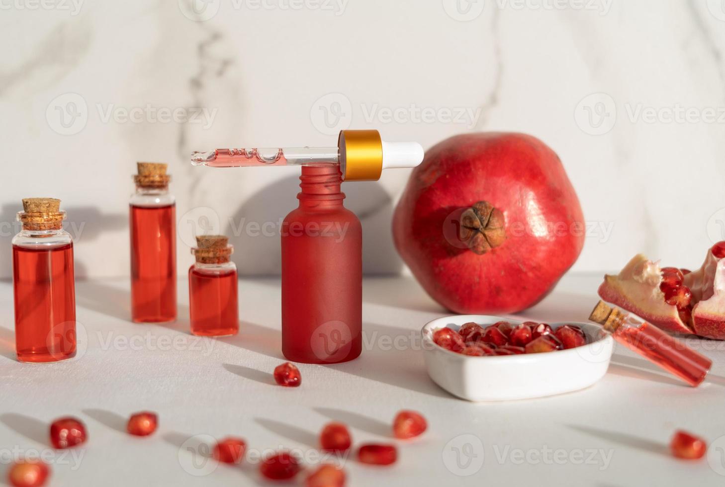 Red dropper bottles of pomegranate serum or oil for face and body standing on a white background photo