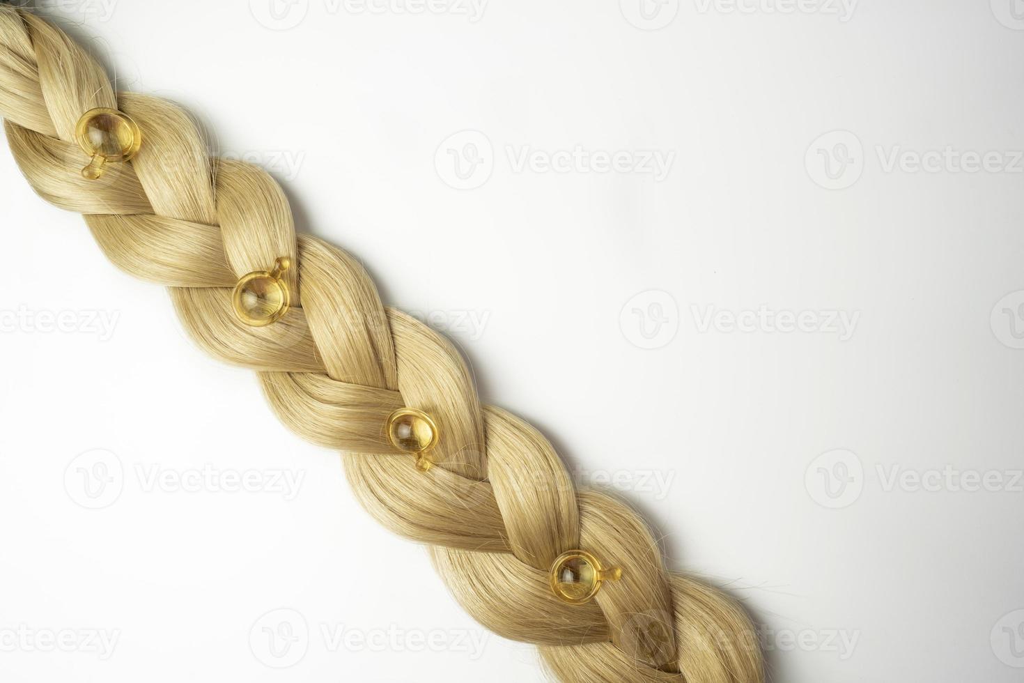 A blonde tress with oil vitamins for hair lying on it photo