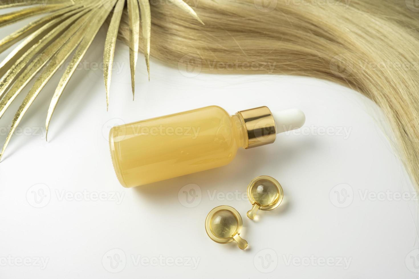 A natural oil or serum for hair care and golden treatment capsules lying on a white background photo