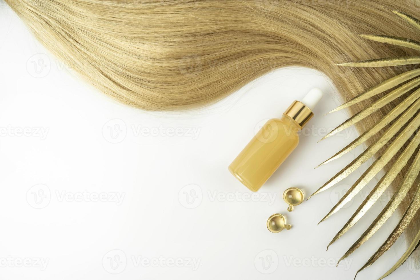 A natural oil or serum for hair care and golden treatment capsules lying on a white background photo