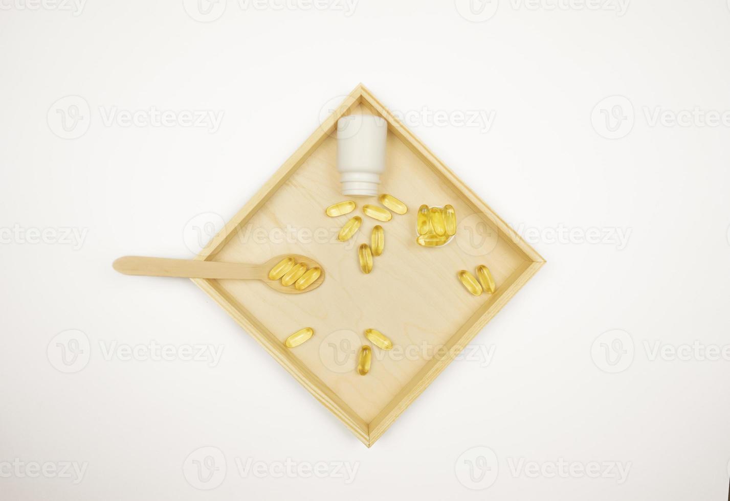 Yellow capsules of Omega 3 lie on a wooden tray photo