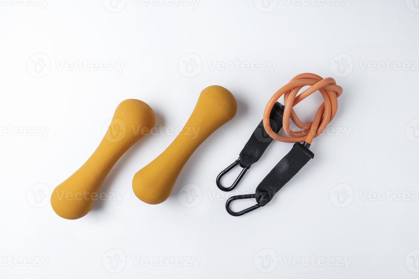 Two orange fitness dumbbells and a fitness expander lying on the white background photo