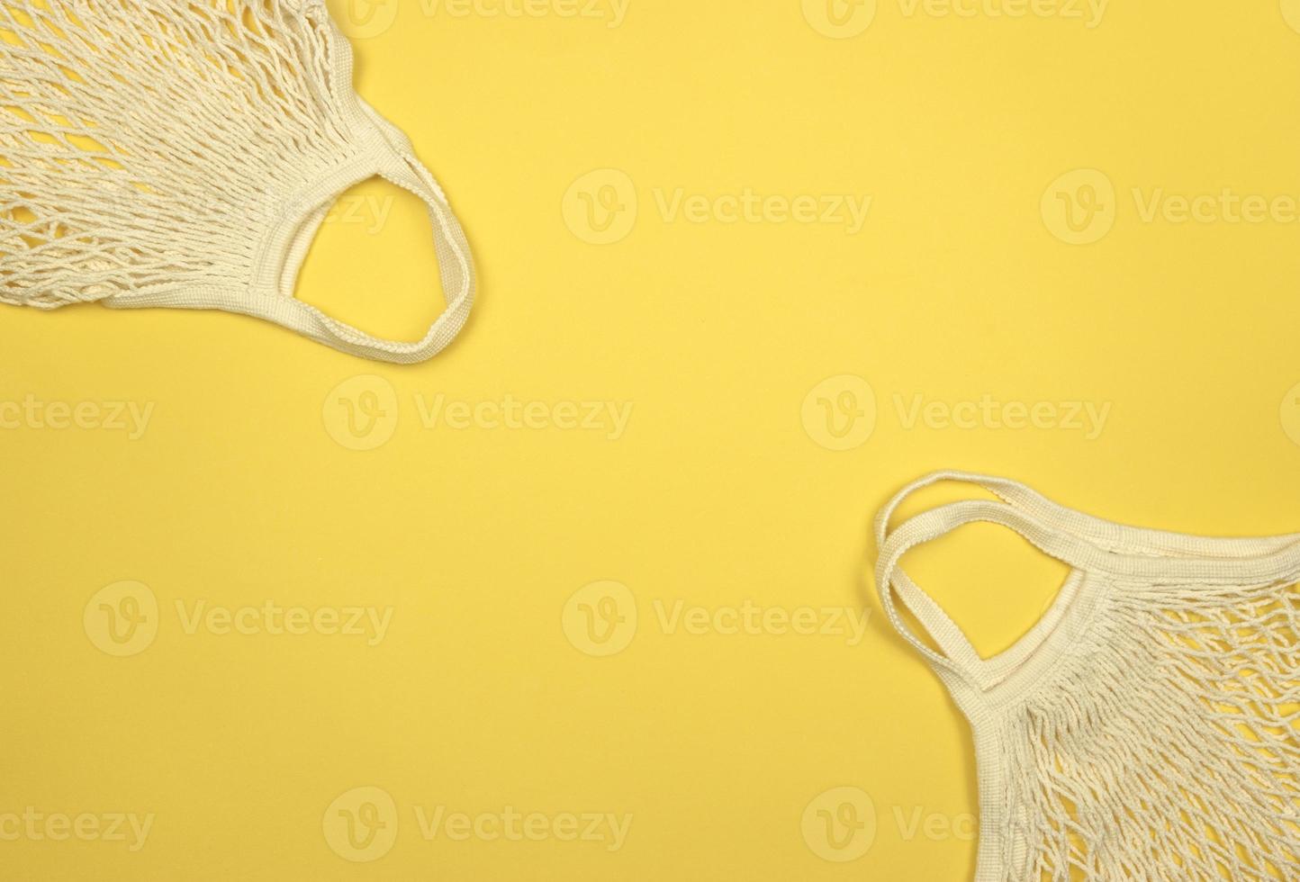 White mesh bags lie on a yellow background. Copy space. Reusable things concept photo